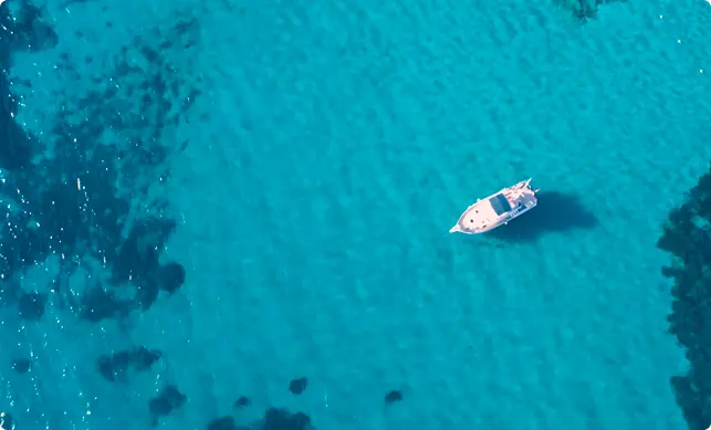 Barco fondeado en aguas turquesas vistas desde el aire